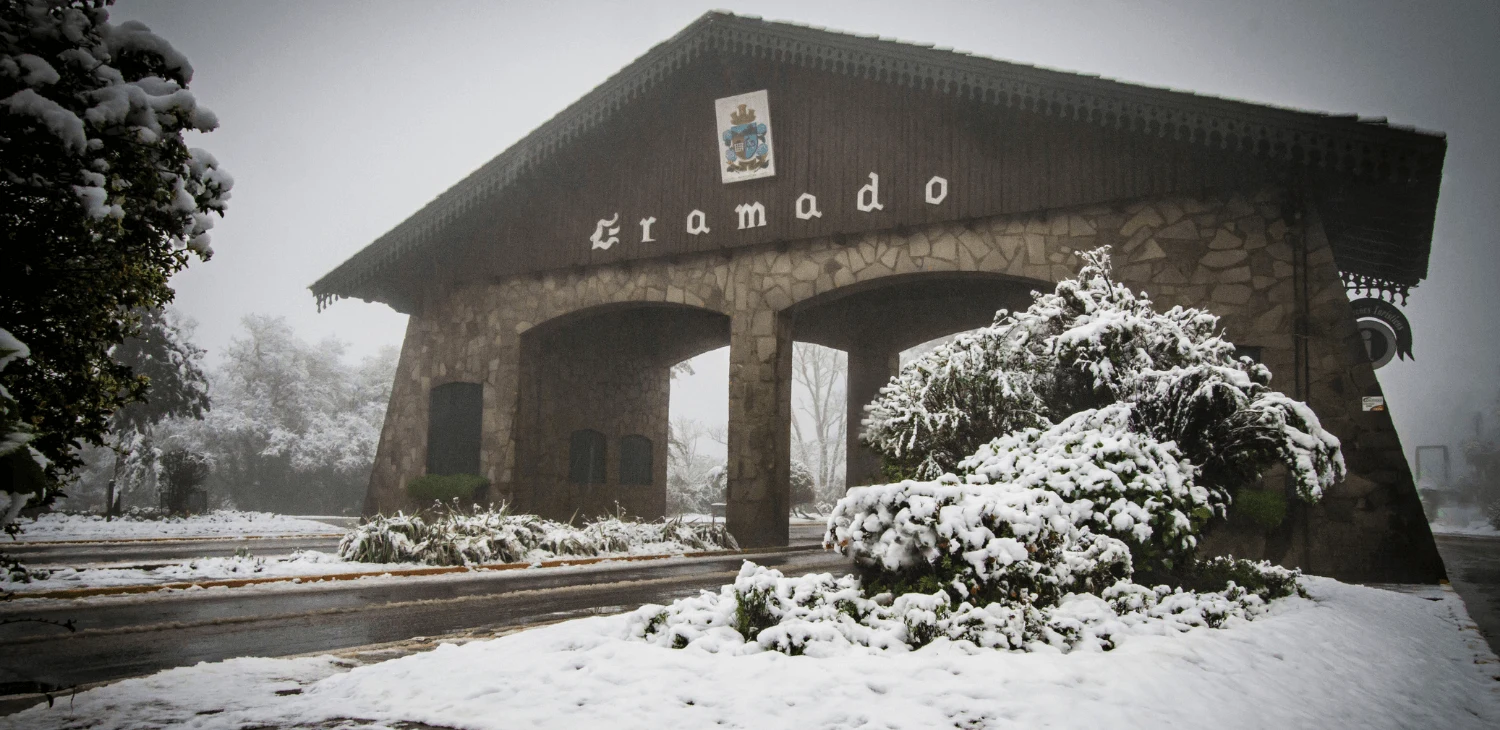 Pórtico de Gramado com céu nublado e árvores cobertas de neve